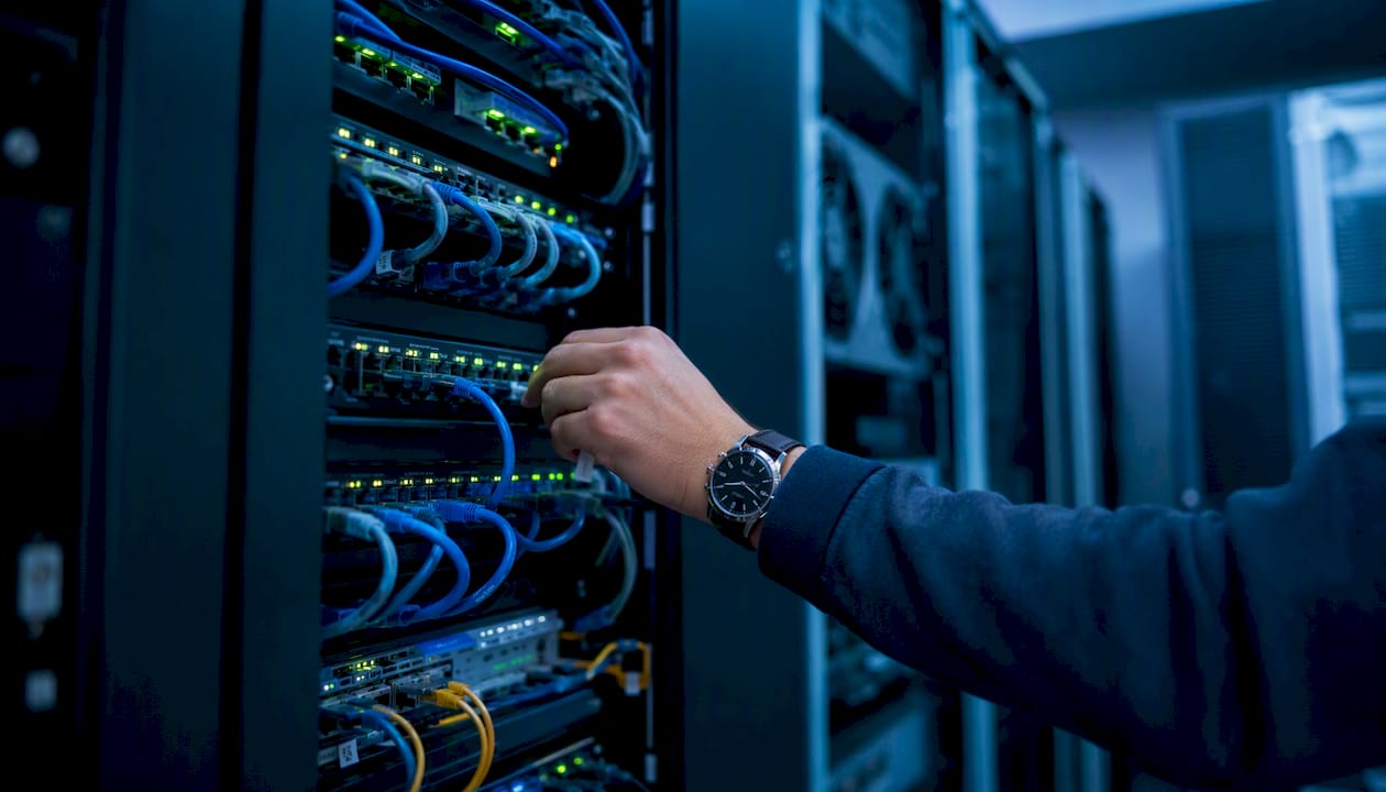 Hand connecting network cable in server rack